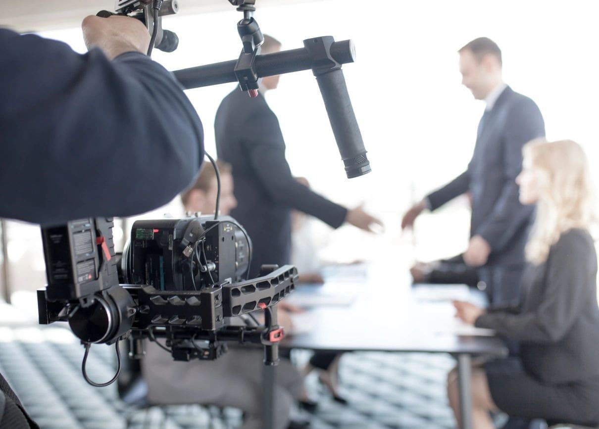 A camera is being used to film people in suits.